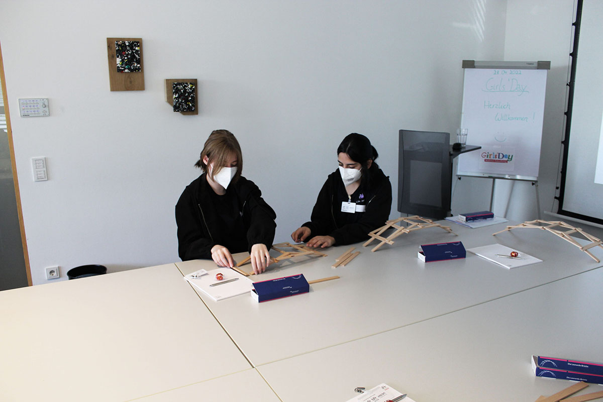 Zwei Schülerinnen konstruieren eine Brücke aus kleinen Holzteilen